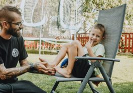 Playful interaction between a father and son in a sunny backyard setting.