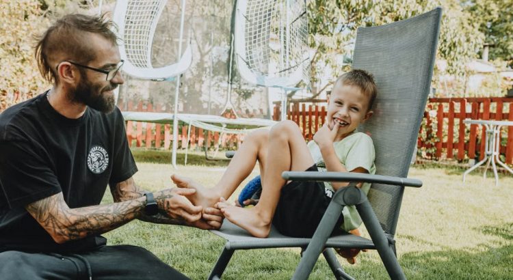 Playful interaction between a father and son in a sunny backyard setting.
